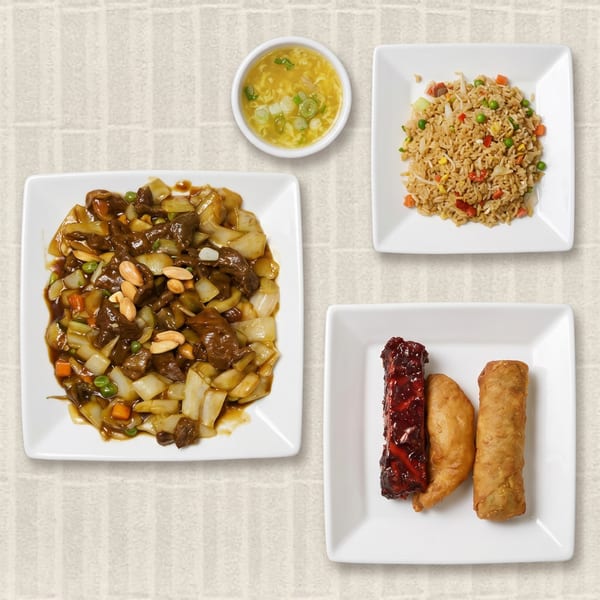 A Chinese food combo meal with beef chop suey, egg drop soup, fried rice, spare rib, and egg roll.