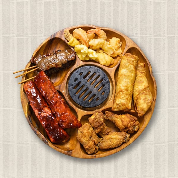 A wooden platter with various appetizers: ribs, skewers, fried shrimp, egg rolls, and chicken wings.