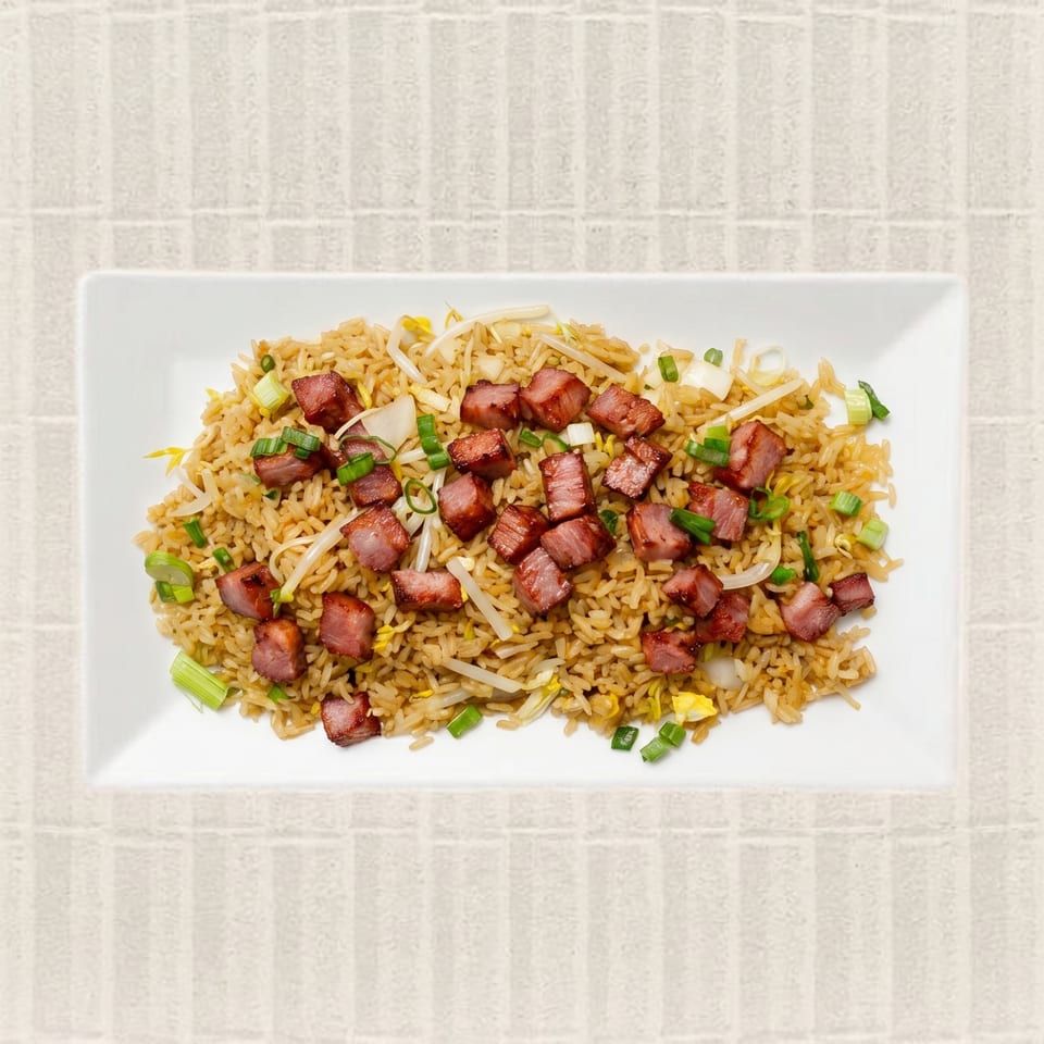 Pork fried rice with bean sprouts, onions, and green onions on a white rectangular plate.