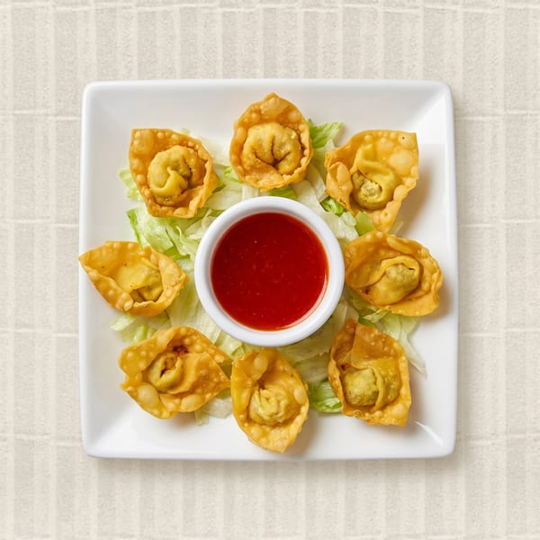 Eight golden-fried wontons arranged around a small bowl of red dipping sauce on a bed of lettuce.